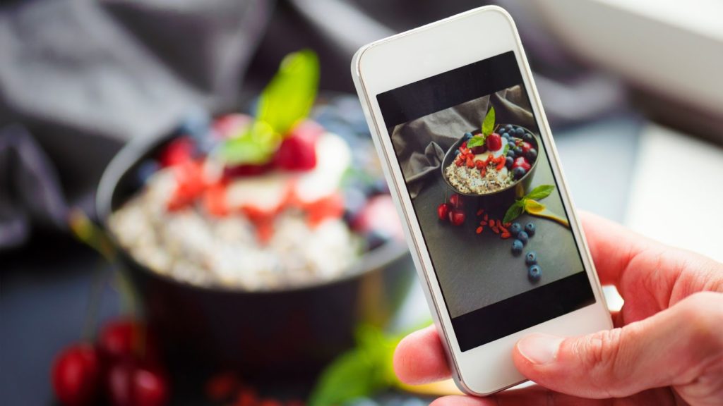 Someone taking a cellphone picture of a bowl of food for a food blog